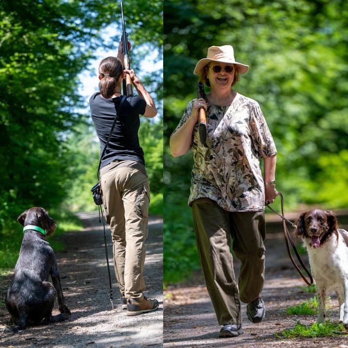 Zwei Personen mit Hund: Links hebt eine Person eine Flinte in einem Waldweg, während ein Hund sitzt; rechts führt eine andere Person mit Hut und Flinte einen Hund an der Leine spazieren.